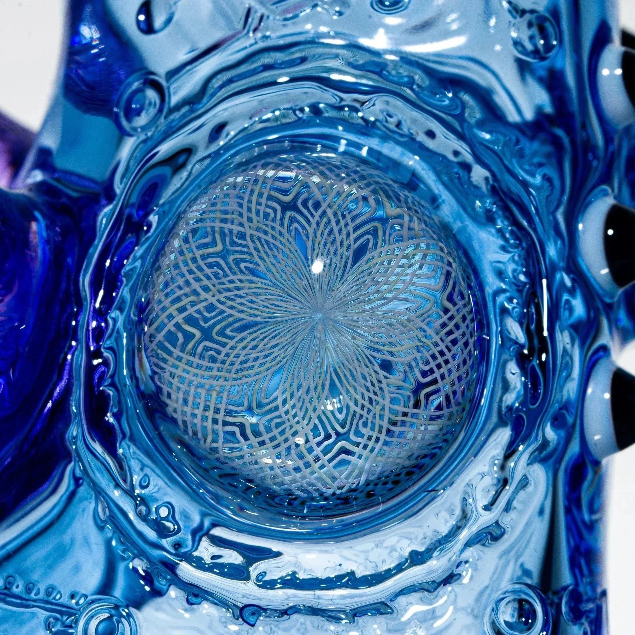 Close-up of intricate blue glass art with detailed geometric flower pattern