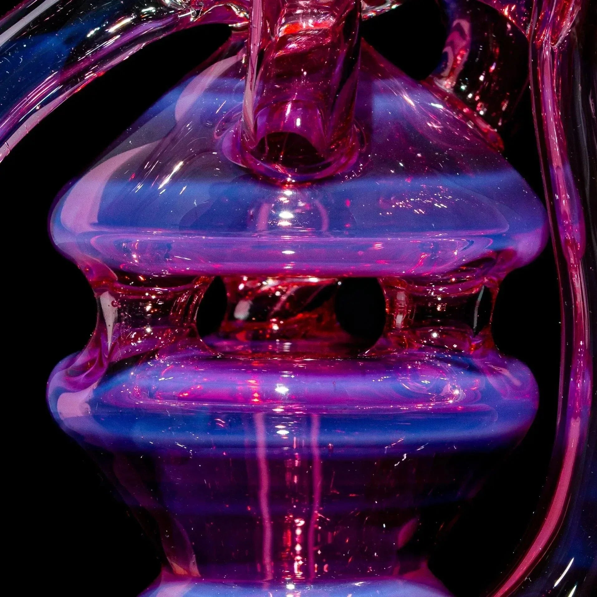 Close-up of a telemagenta and blue glass recycler with intricate details, smoke shop glassware