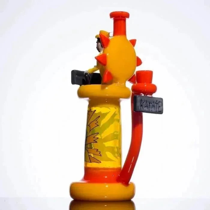 Colorful glass bong with yellow sun design, orange accents, and 'KARATE' tag, heady glass art piece