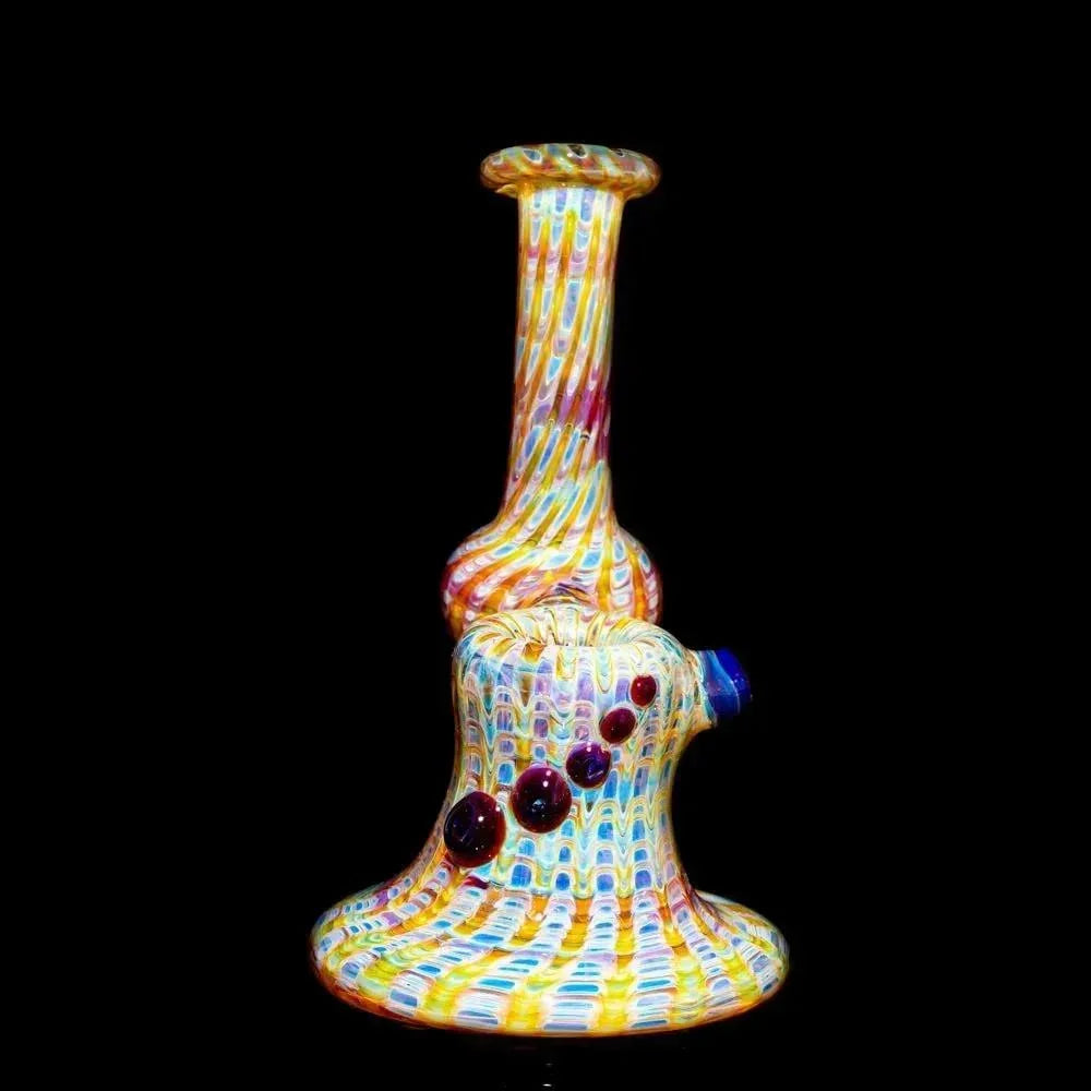 Amber purple wrap glass bubbler with colorful rake pattern and dot accents on black background.