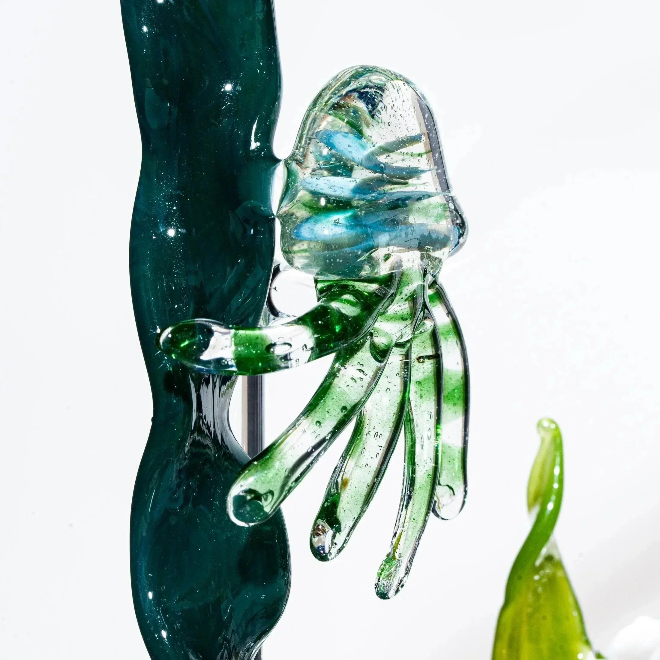 Handcrafted glass jellyfish sculpture with green, blue, and clear details, kinetic art