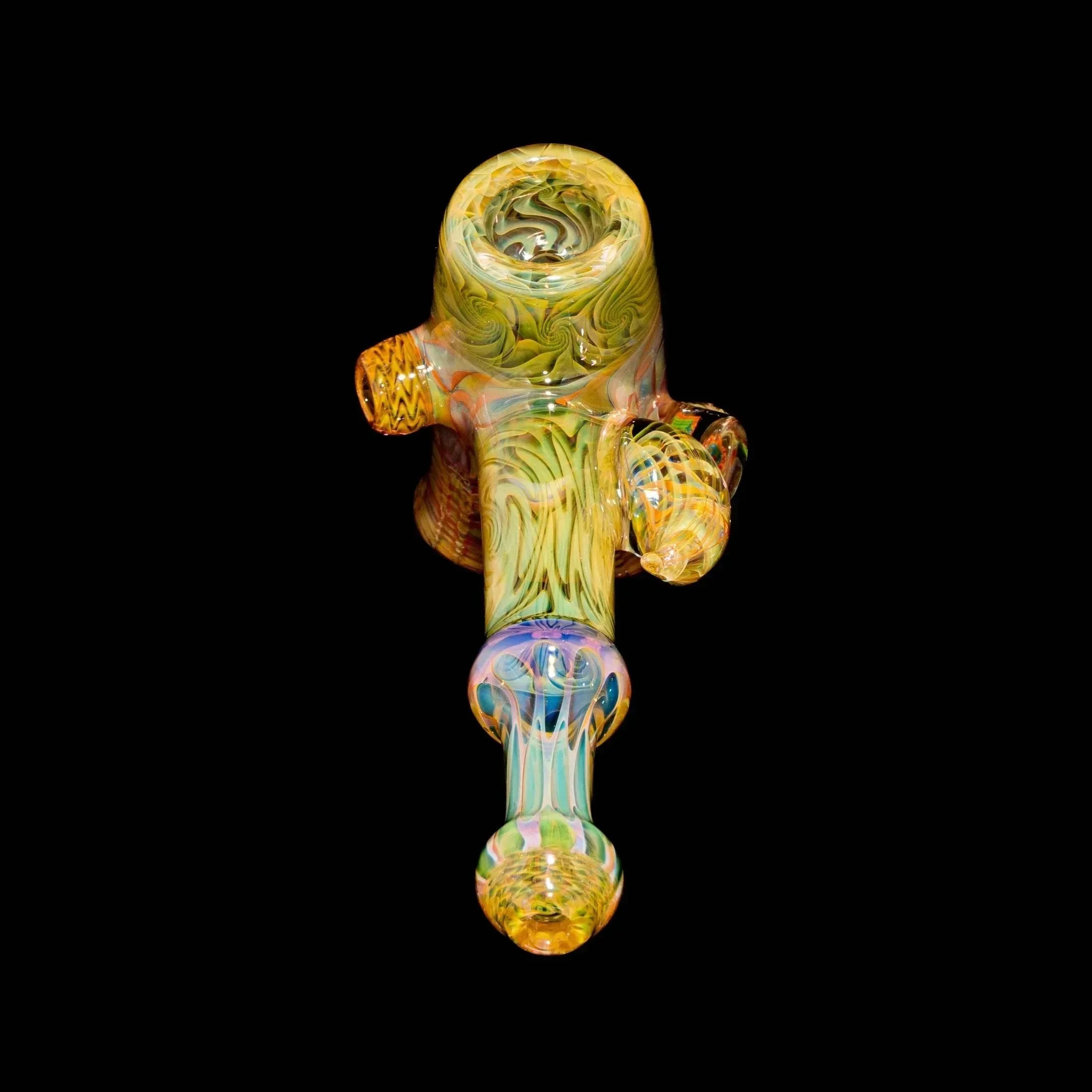 Heady glass hand pipe with intricate yellow and green swirls on black background