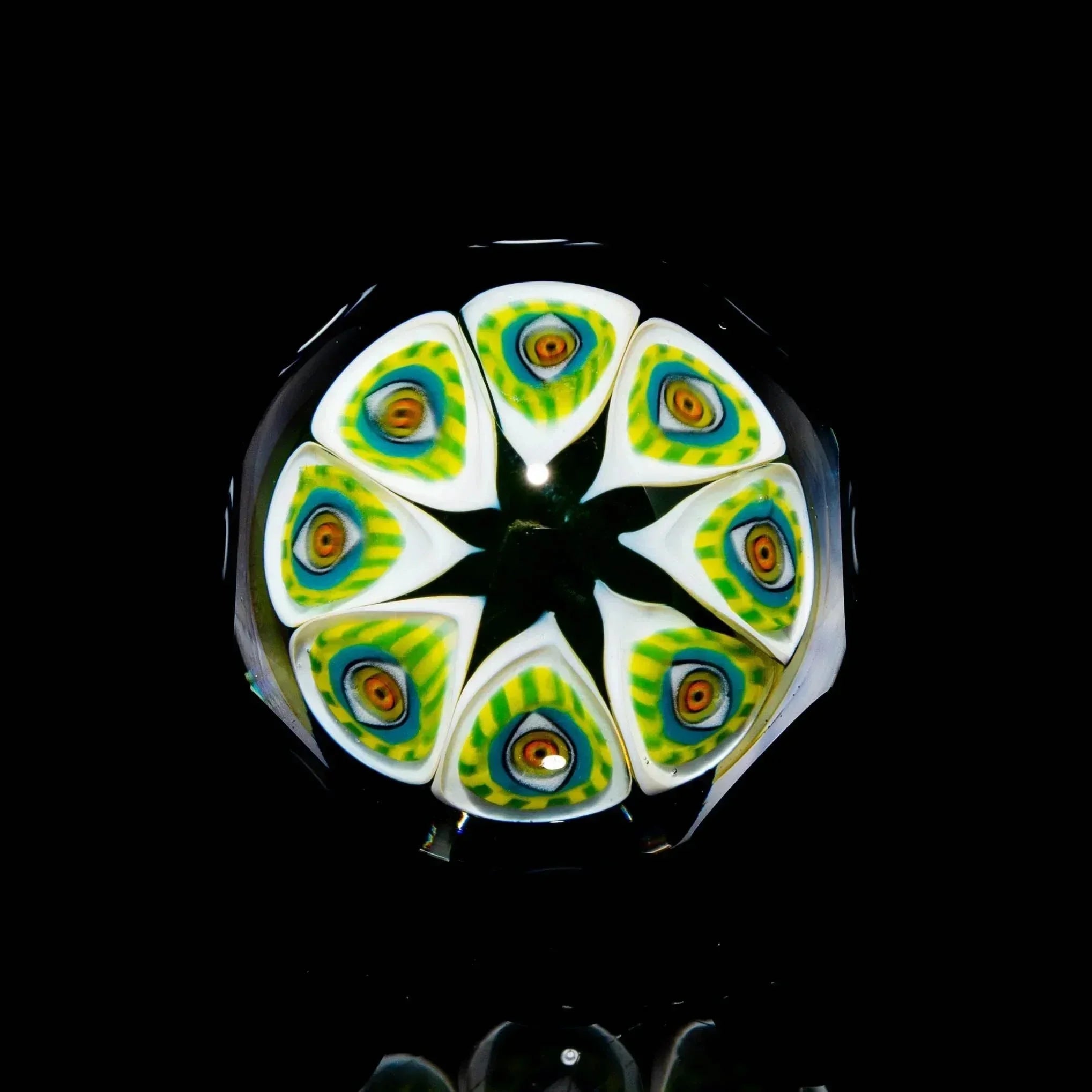 Colorful patterned glass marble with green, yellow, and orange detailed design on black background