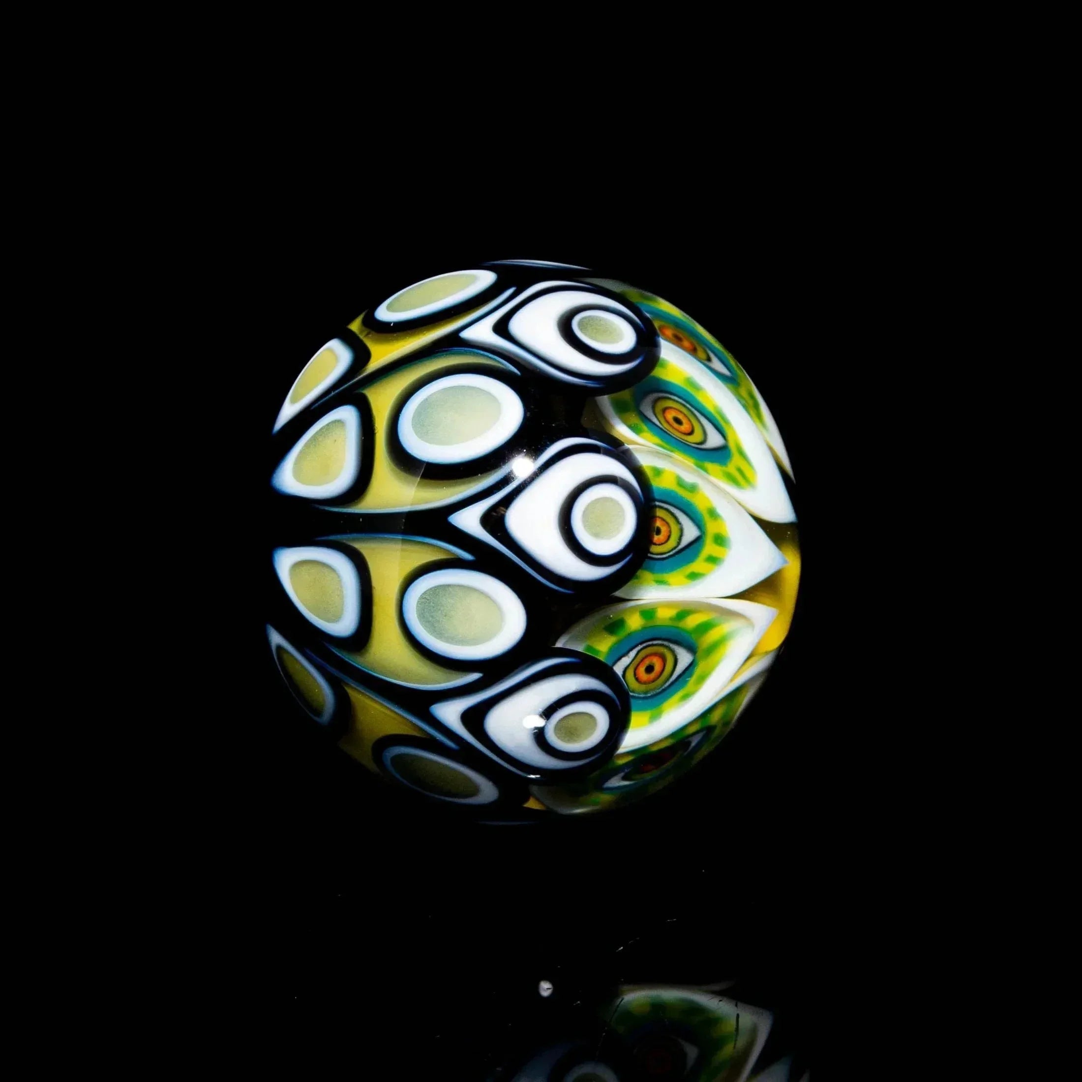 Handcrafted glass marble with intricate millefiori patterns in yellow, green, black and white