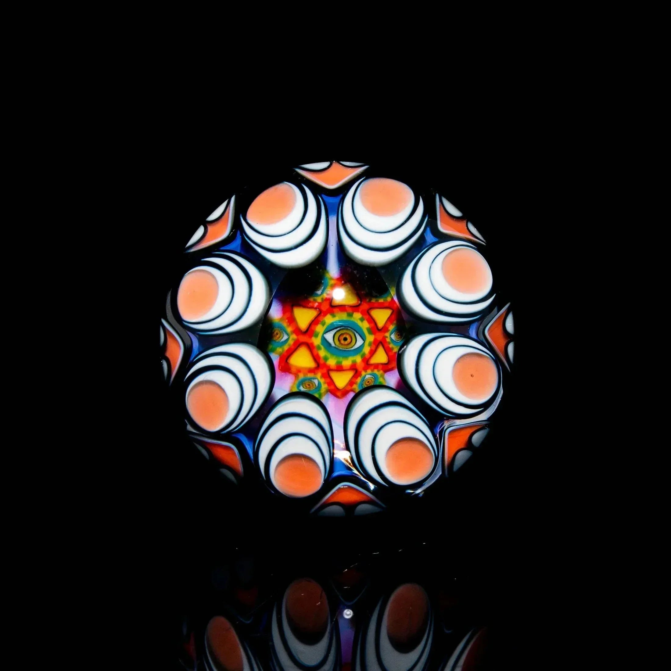Colorful glass marble with intricate psychedelic patterns and a central eye design on black background