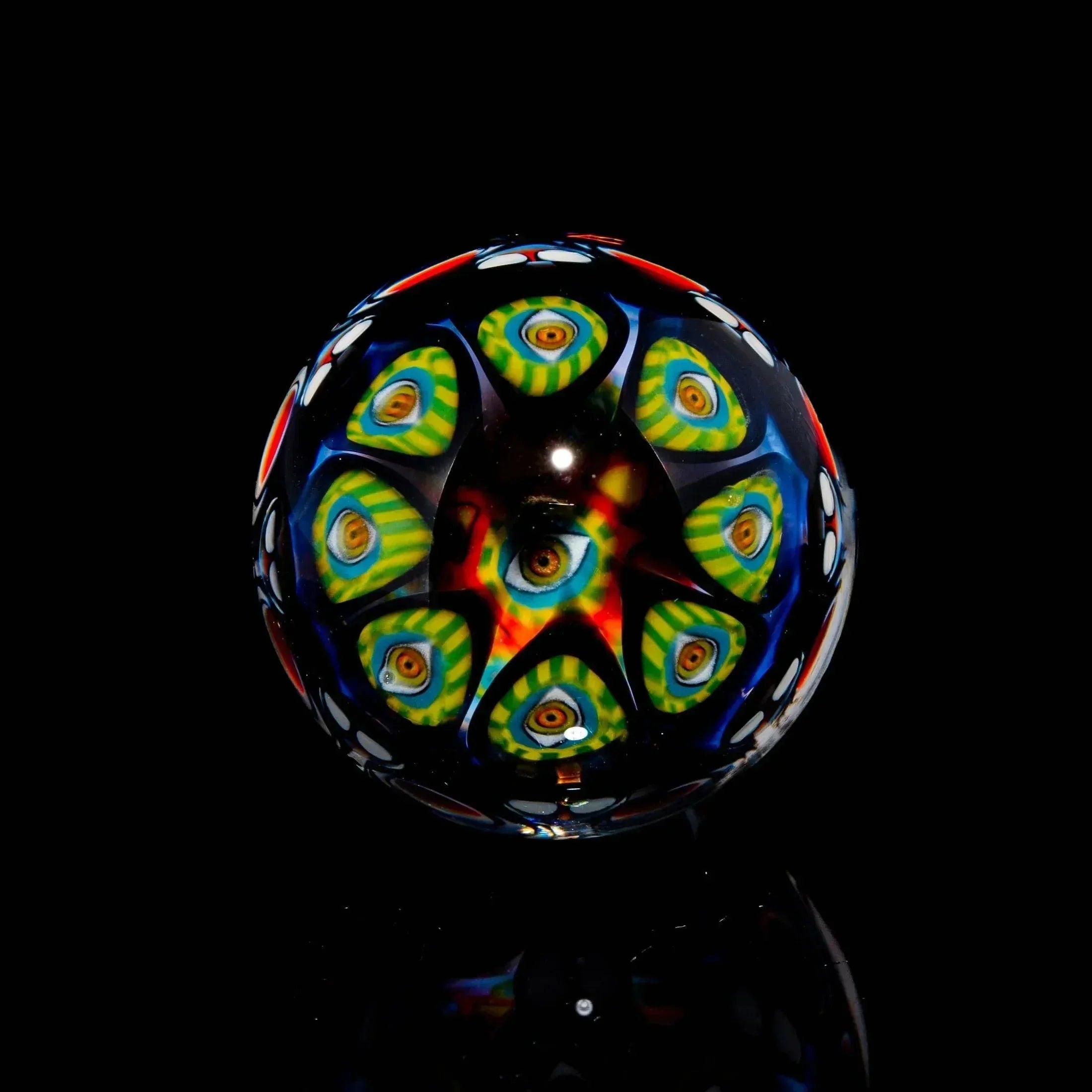 Heady glass marble with colorful geometric eye patterns on a black background