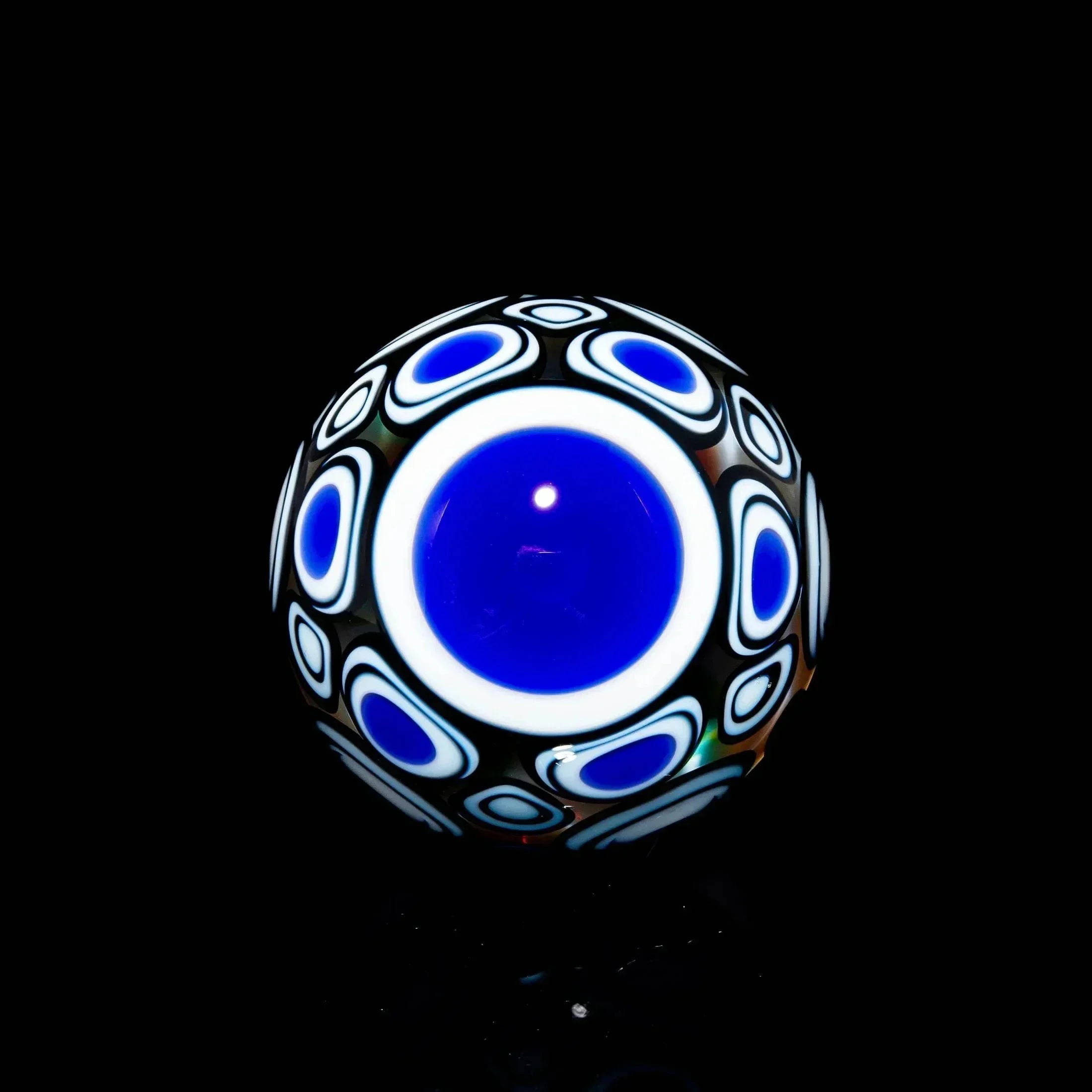 Handcrafted glass marble with blue and white geometric patterns on a black background