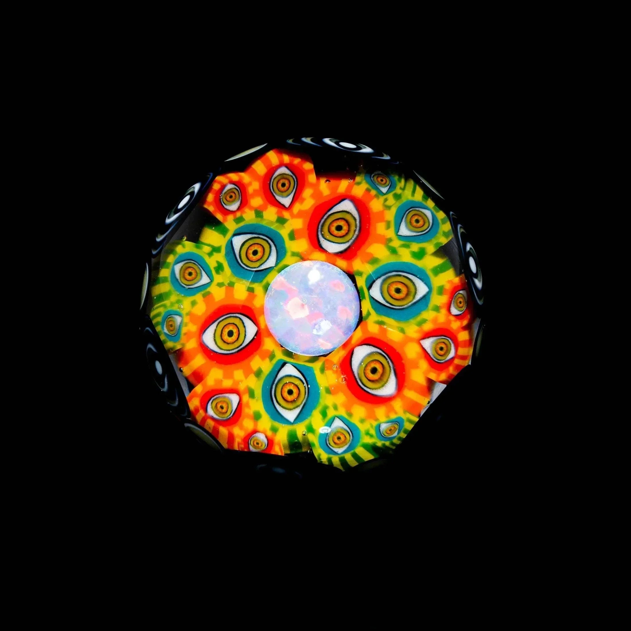 Colorful glass marble with intricate psychedelic pattern and central opal core on black background