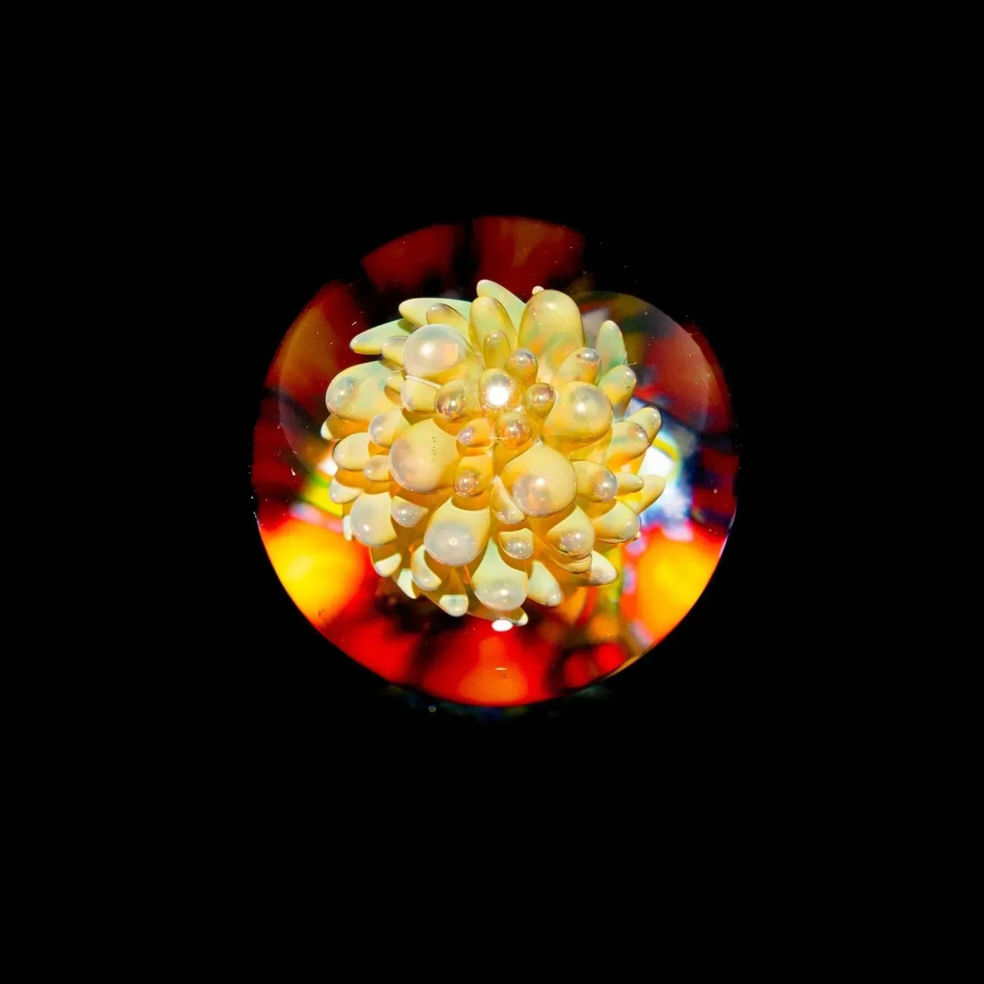Intricate yellow glass marble with bubble accents and vibrant, colorful background