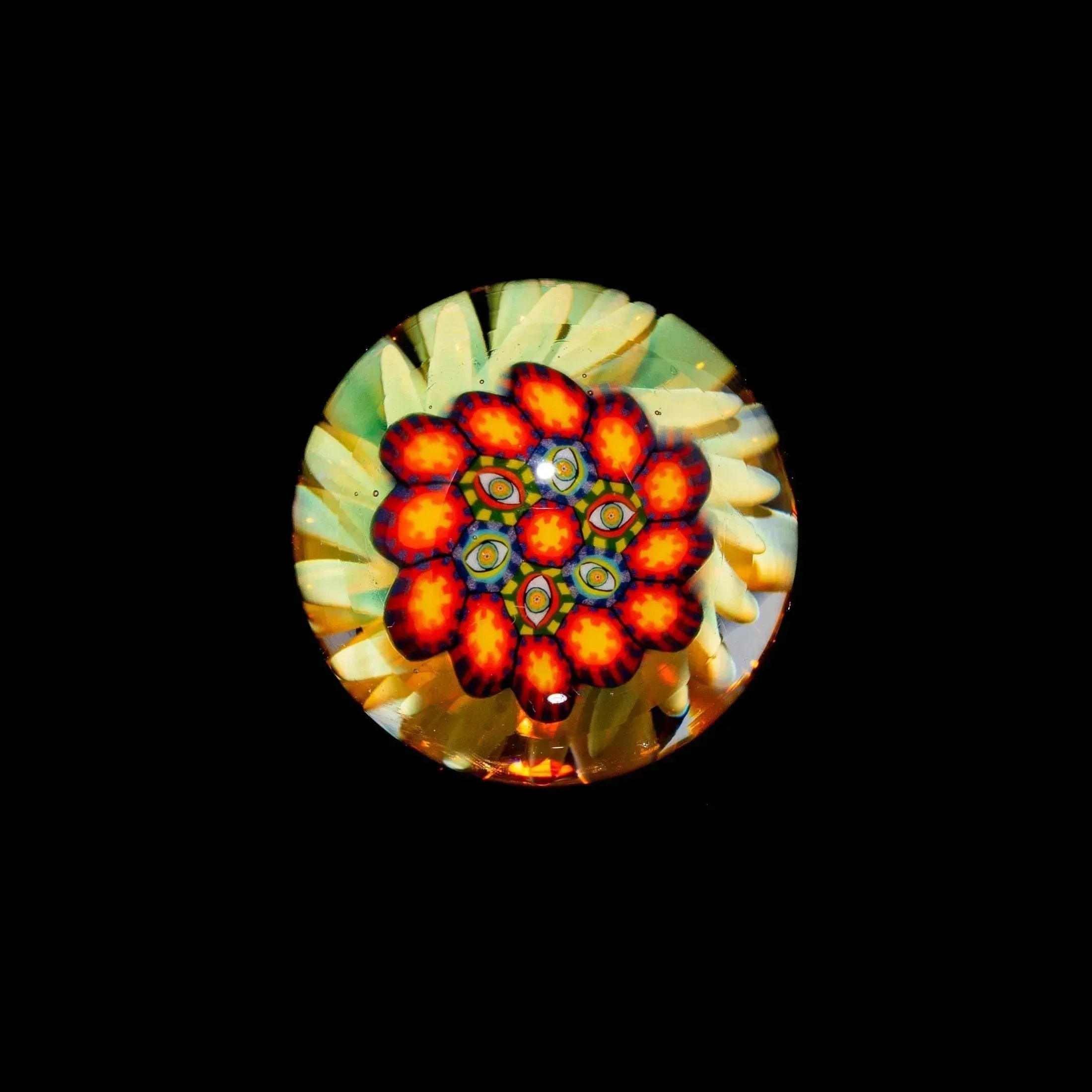 Colorful glass marble with vibrant flower and eye pattern on a black background