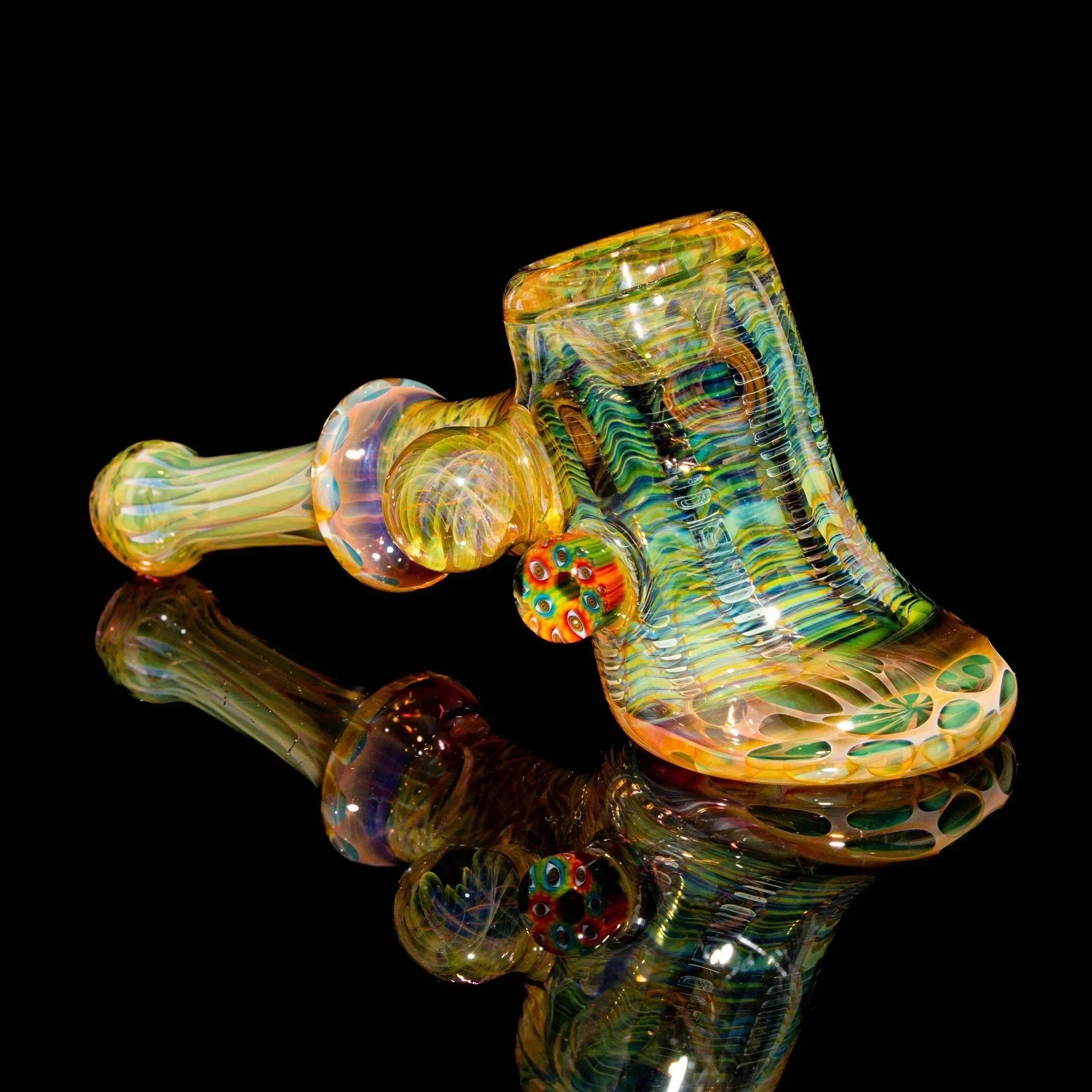 Heady glass hand pipe with colorful swirls and sculpted details on a black background