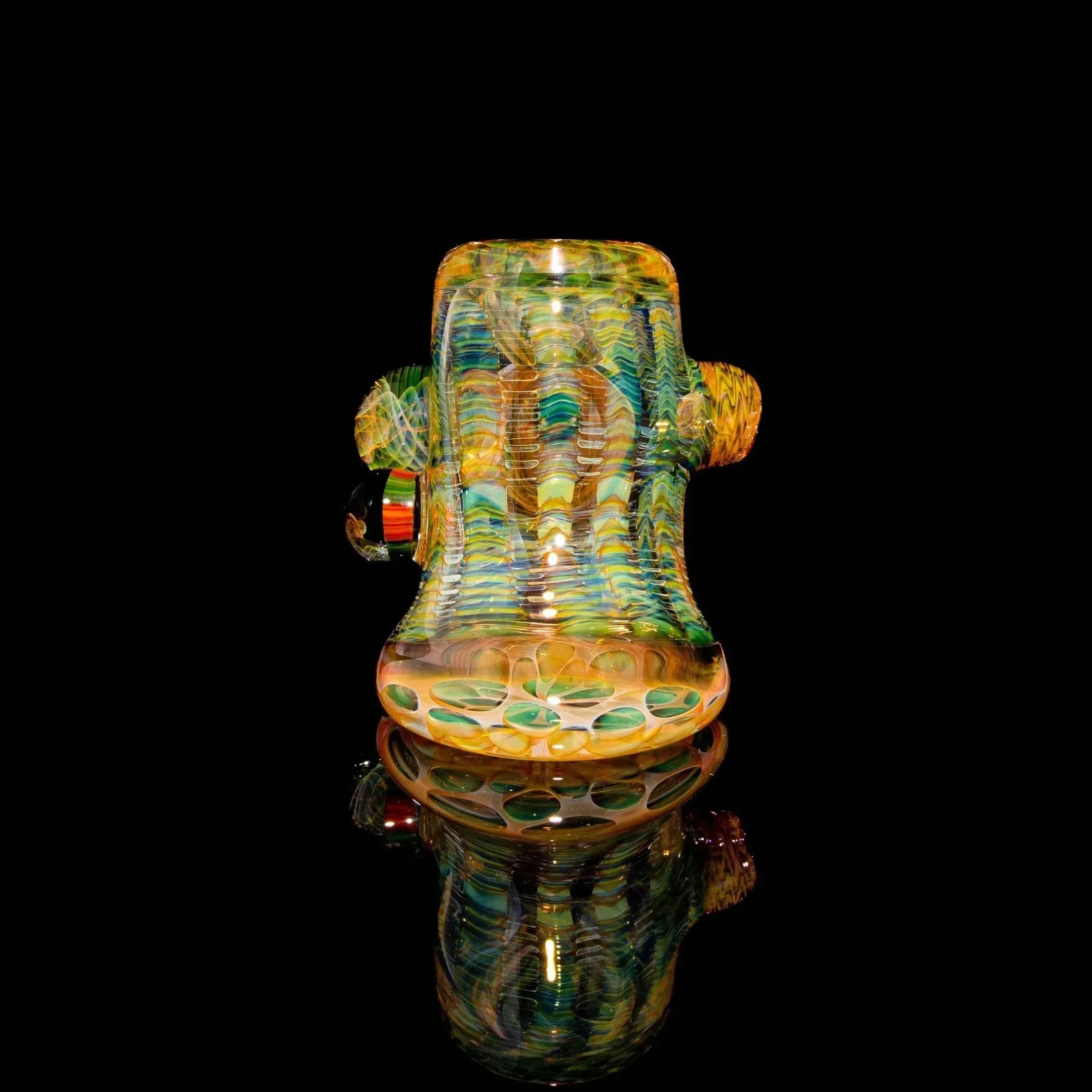 Heady glass water pipe with intricate multicolor patterns on black reflective surface.