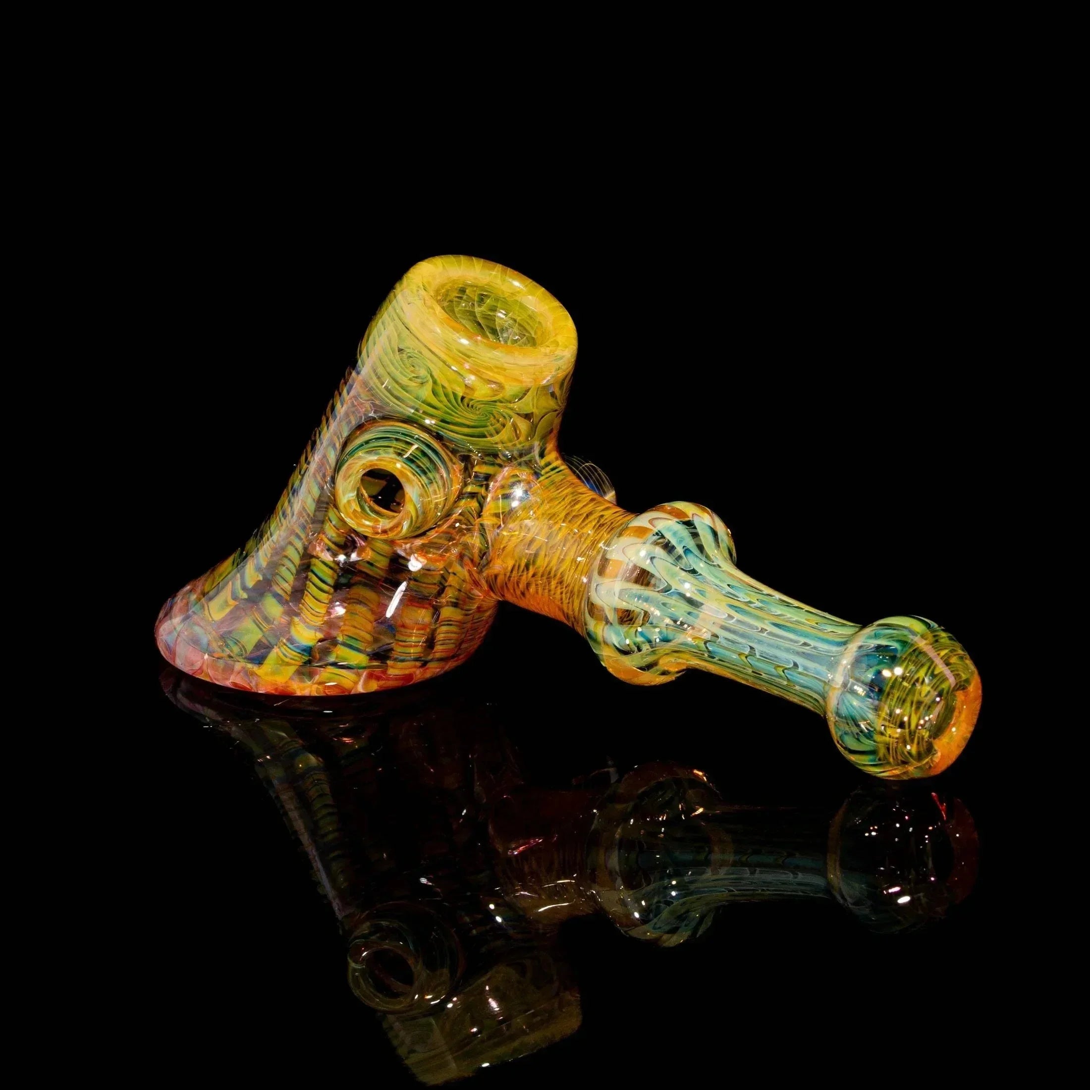 Colorful heady glass hand pipe with intricate patterns on black background