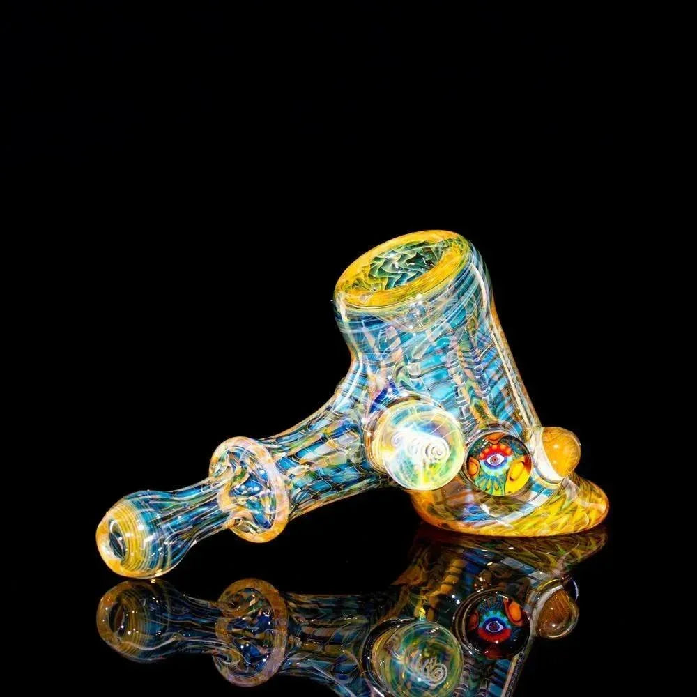Colorful heady glass hammer pipe with intricate patterns on a black reflective surface