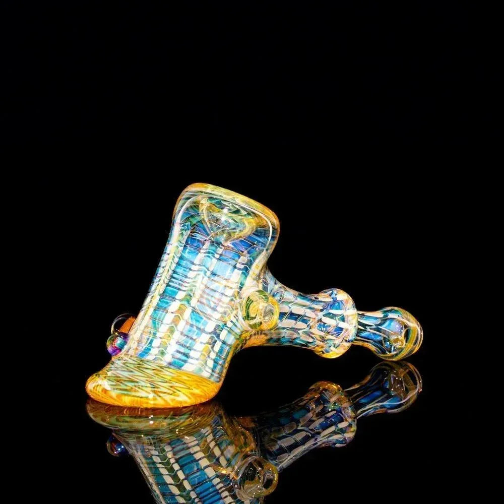 Colorful heady glass hammer pipe with intricate patterns on a black reflective surface