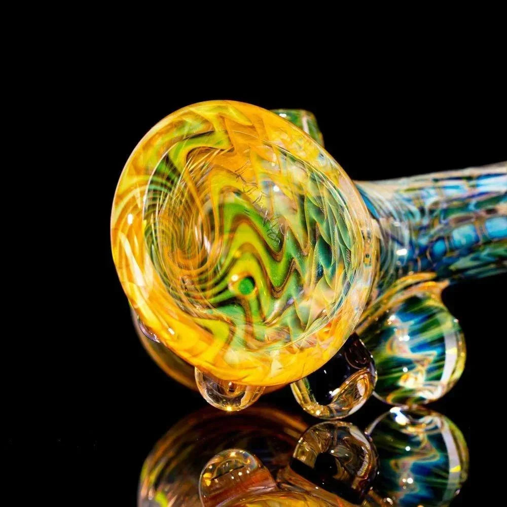 Handcrafted glass pipe with yellow, green, and blue swirling patterns on a black background