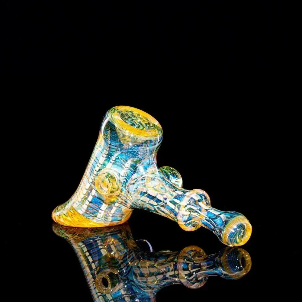 Colorful heady glass pipe with yellow and blue patterns on a black reflective surface
