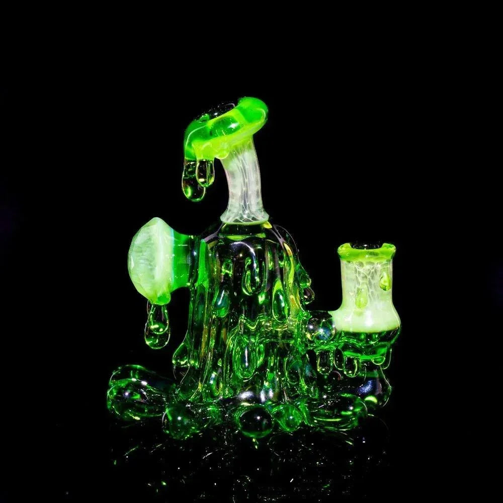 Neon green glass mini rig with splatter design and matching cap on black background.