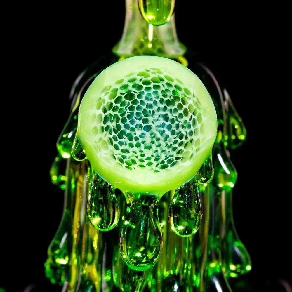 Close-up of a green glass mini rig with splatter and honeycomb accents on black background