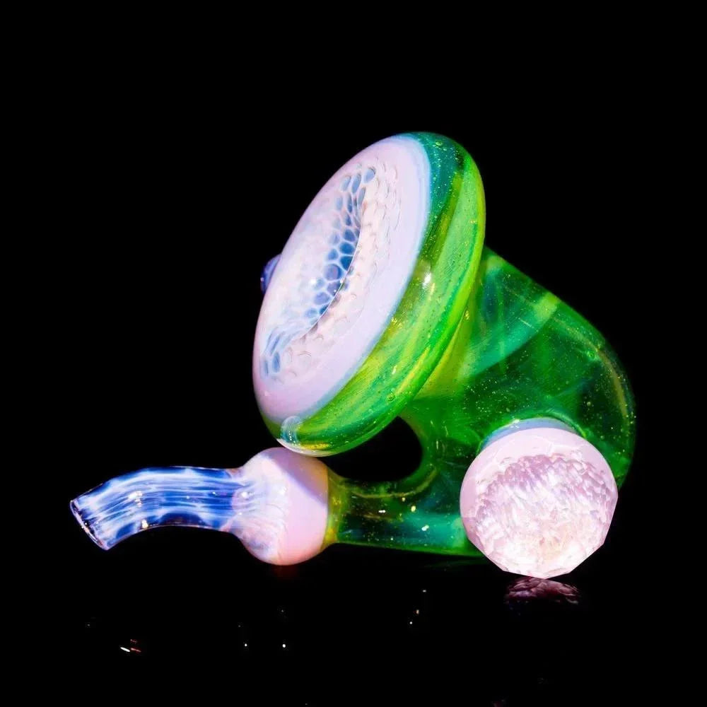 Faceted honeycomb sherlock glass pipe with green and pink accents on black background.