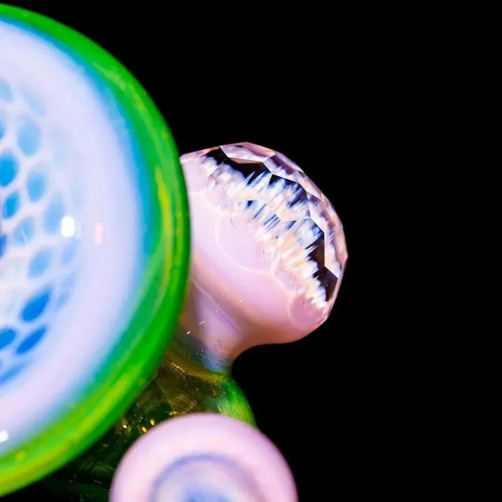 Close-up of a faceted honeycomb pattern sherlock glass pipe with green and blue accents