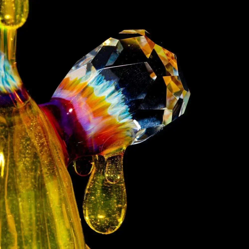 Close-up of colorful heady glass flask with faceted crystal and drop details on black background
