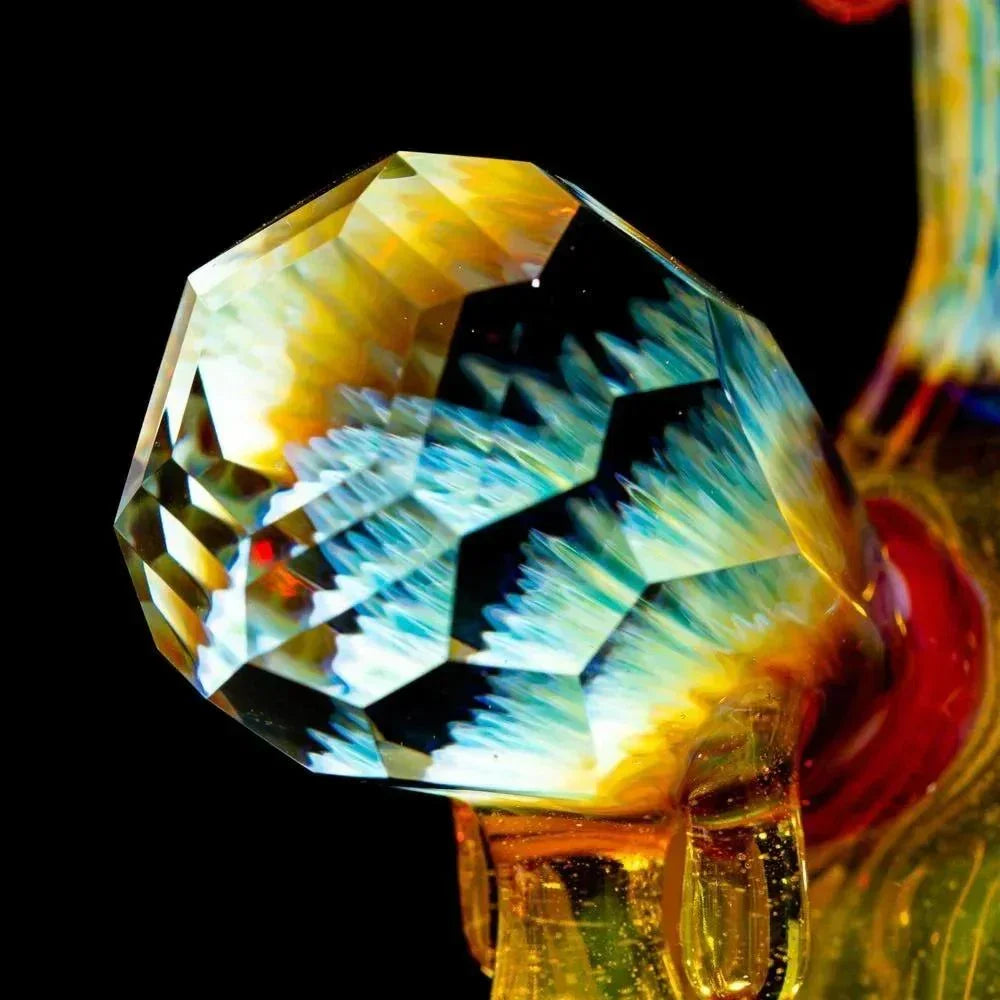 Faceted art glass cap with blue, yellow, and clear crystal patterns, close-up view