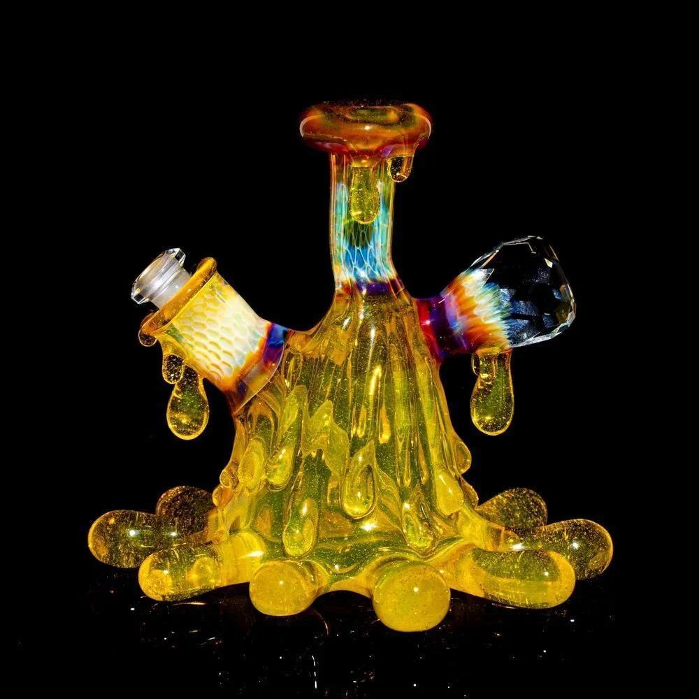 Colorful heady glass rig with yellow drip design and matching cap on black background