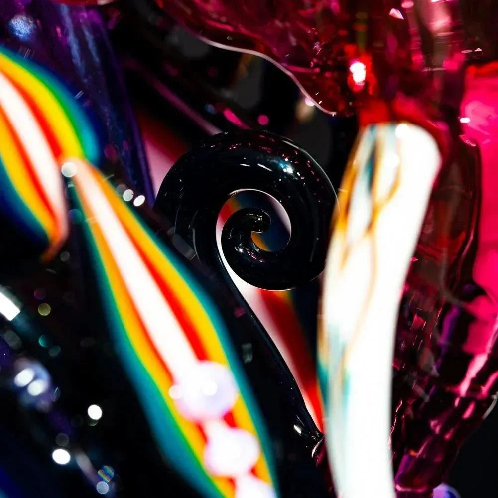 Close-up of colorful glass art recycler with rainbow stripes and swirling design details.