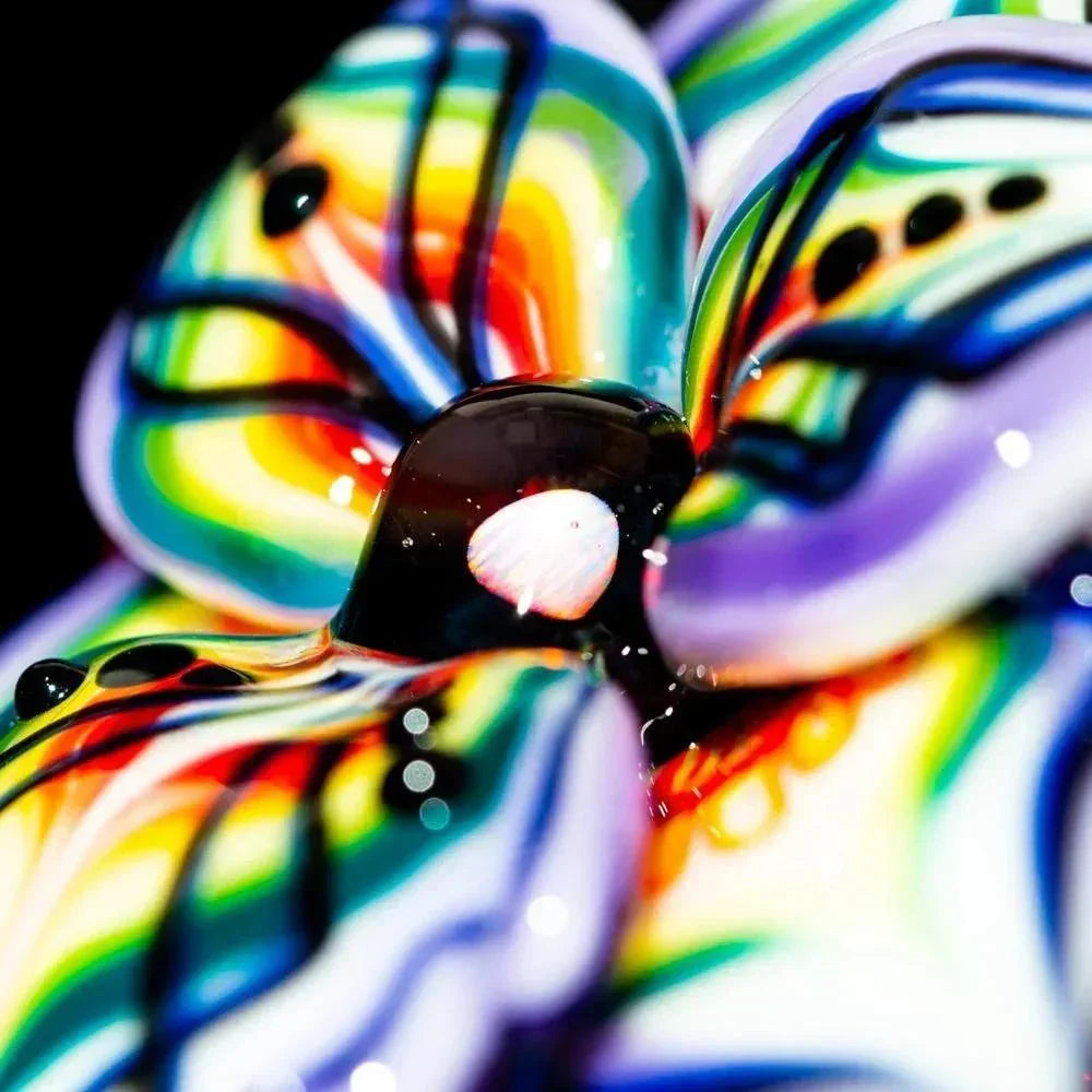 Colorful close-up of a glass flower with vibrant rainbow patterns and black accents.