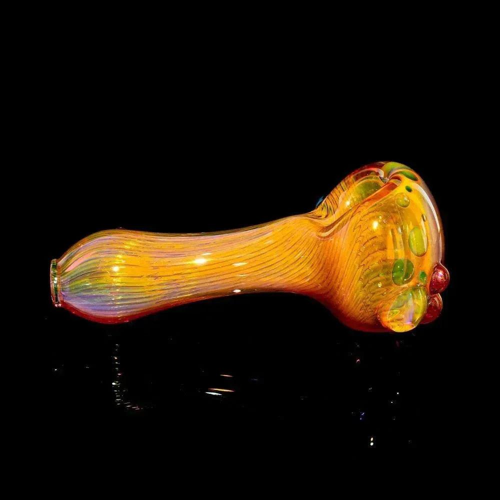 Gold fumed glass spoon pipe with green accents on a black background