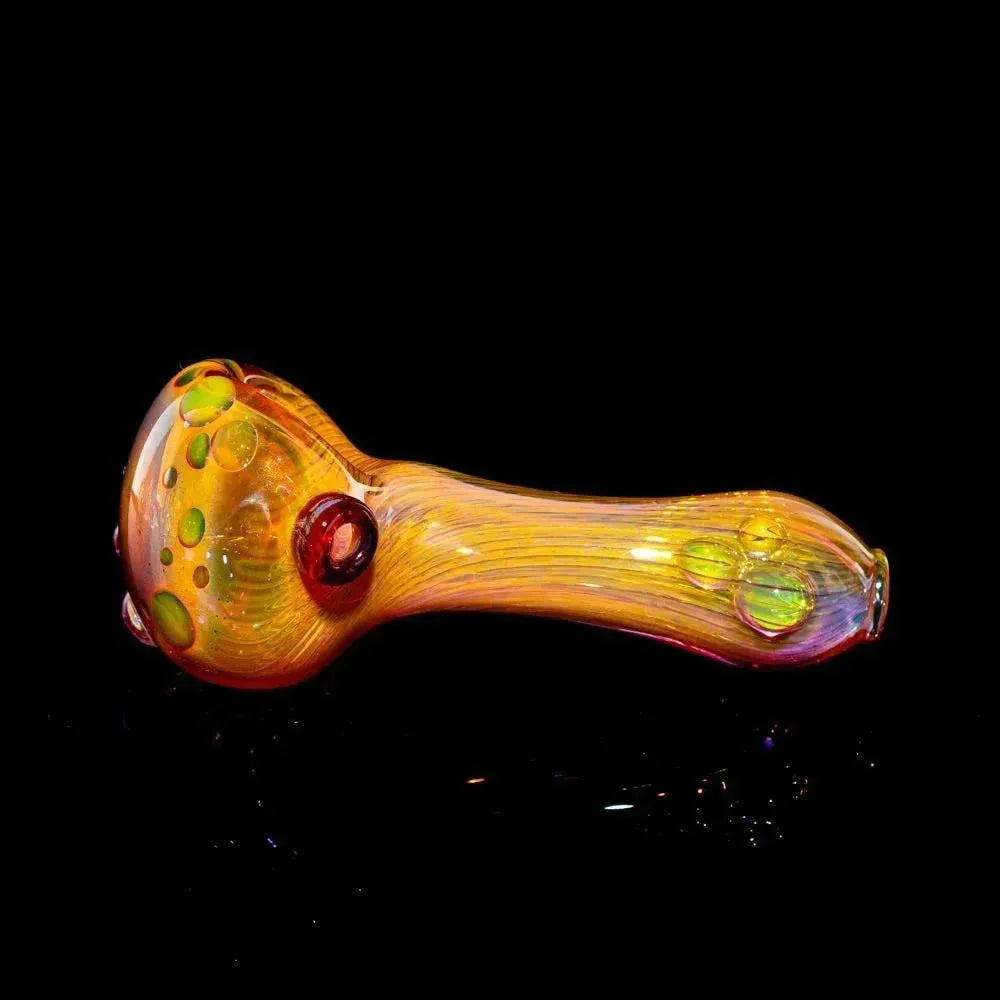 Gold fumed glass spoon pipe with colorful accents on black background
