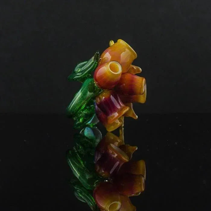 Colorful hand-blown glass pipe with amber and green swirls, reflective surface