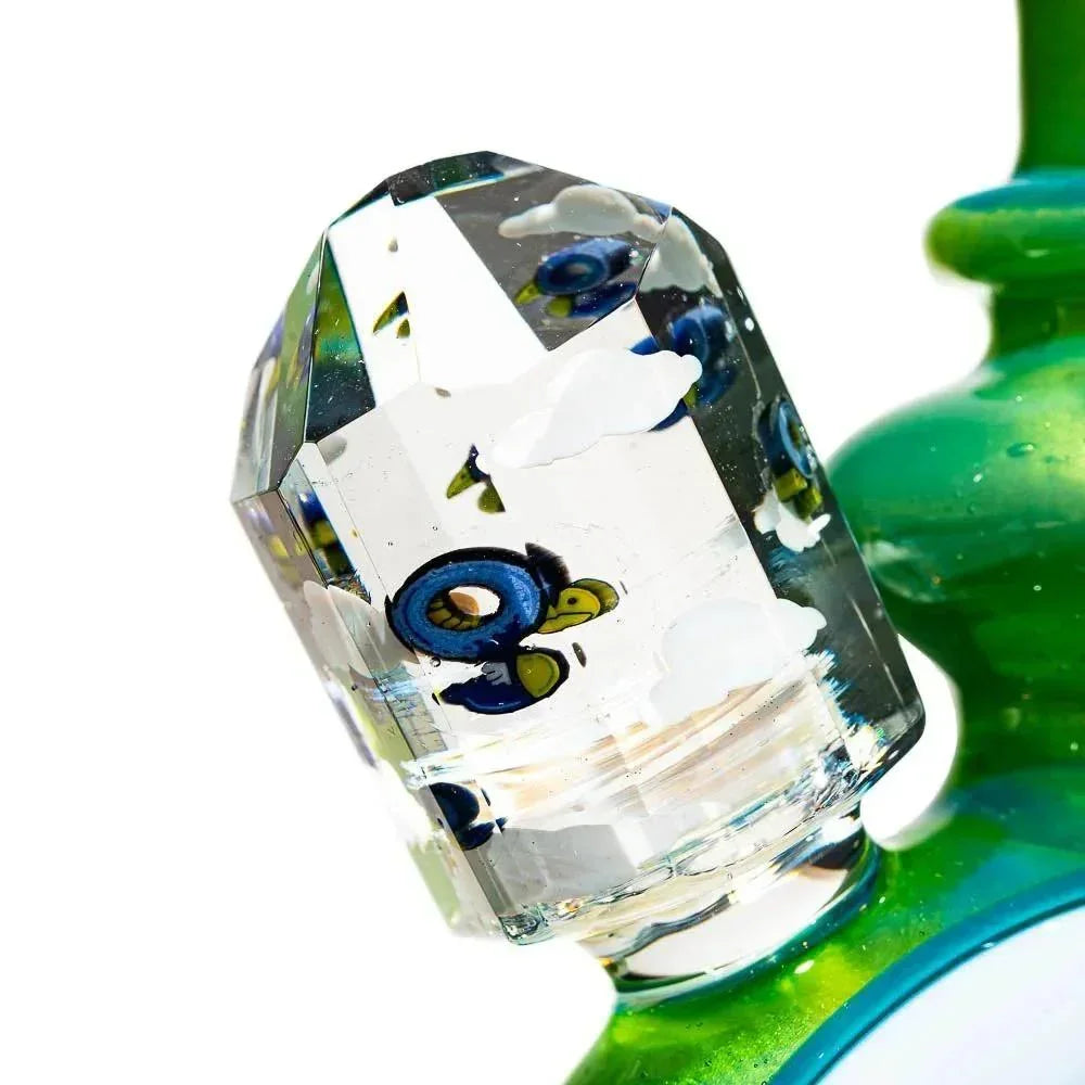 Close-up of a green glass water pipe with faceted glass detail and colorful internal accents