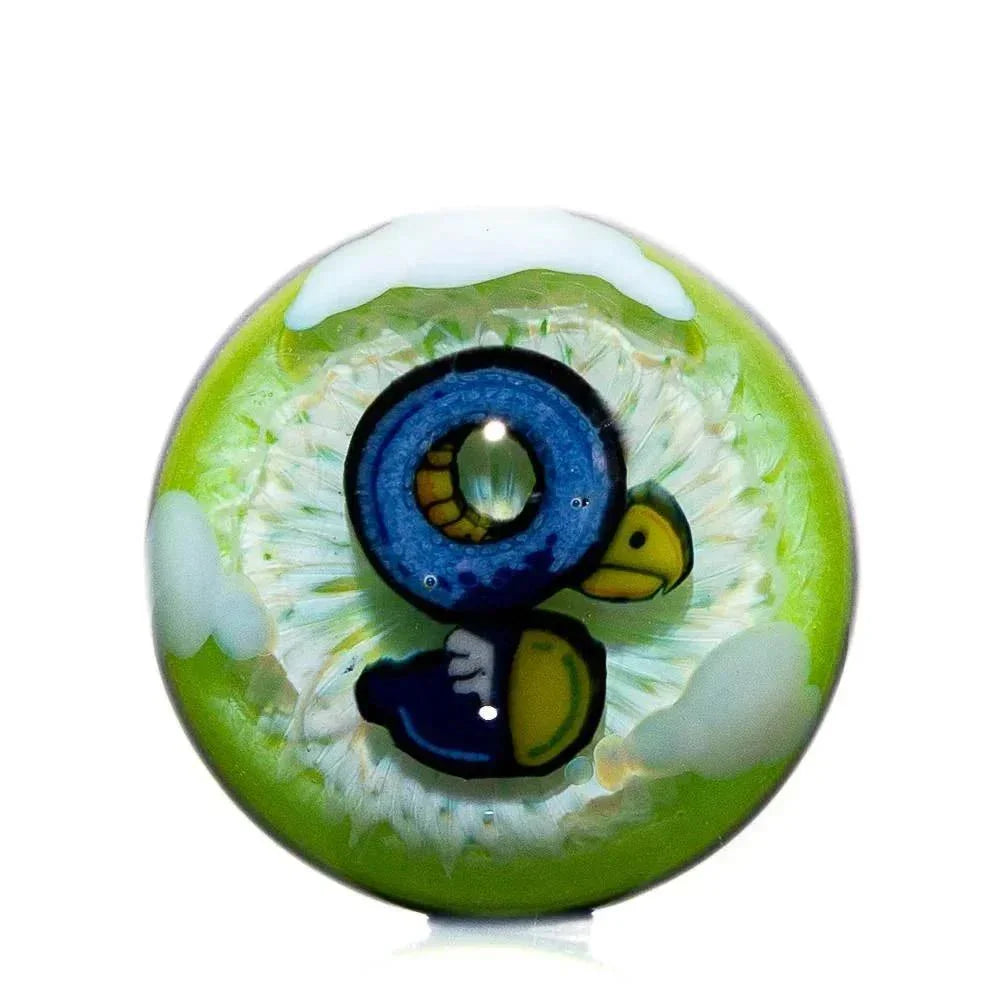 Handcrafted glass marble with colorful bird design and green background