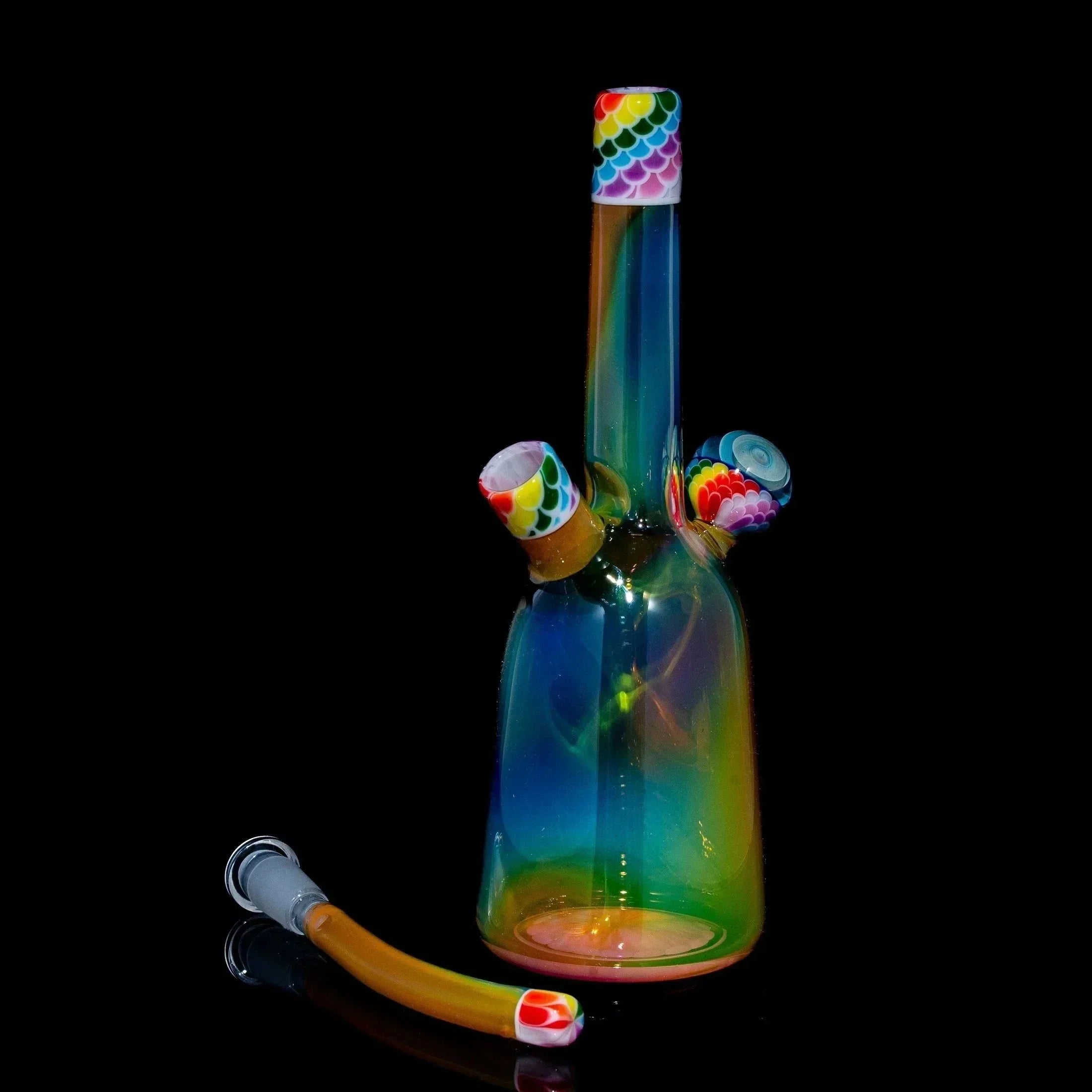 Colorful glass water pipe rig with rainbow accents and matching sherlock cap on black background