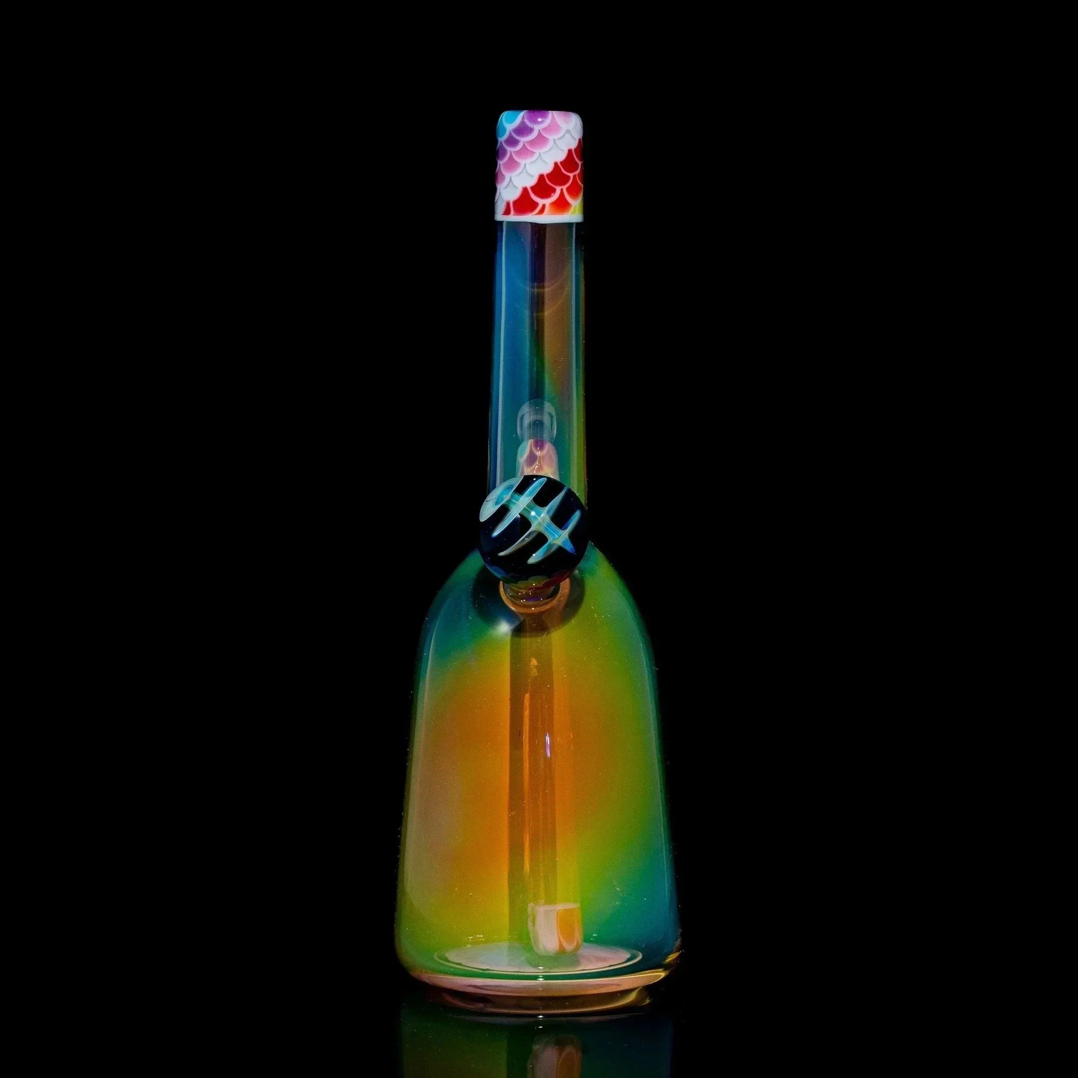 Colorful rainbow glass rig with a patterned cap on a black background