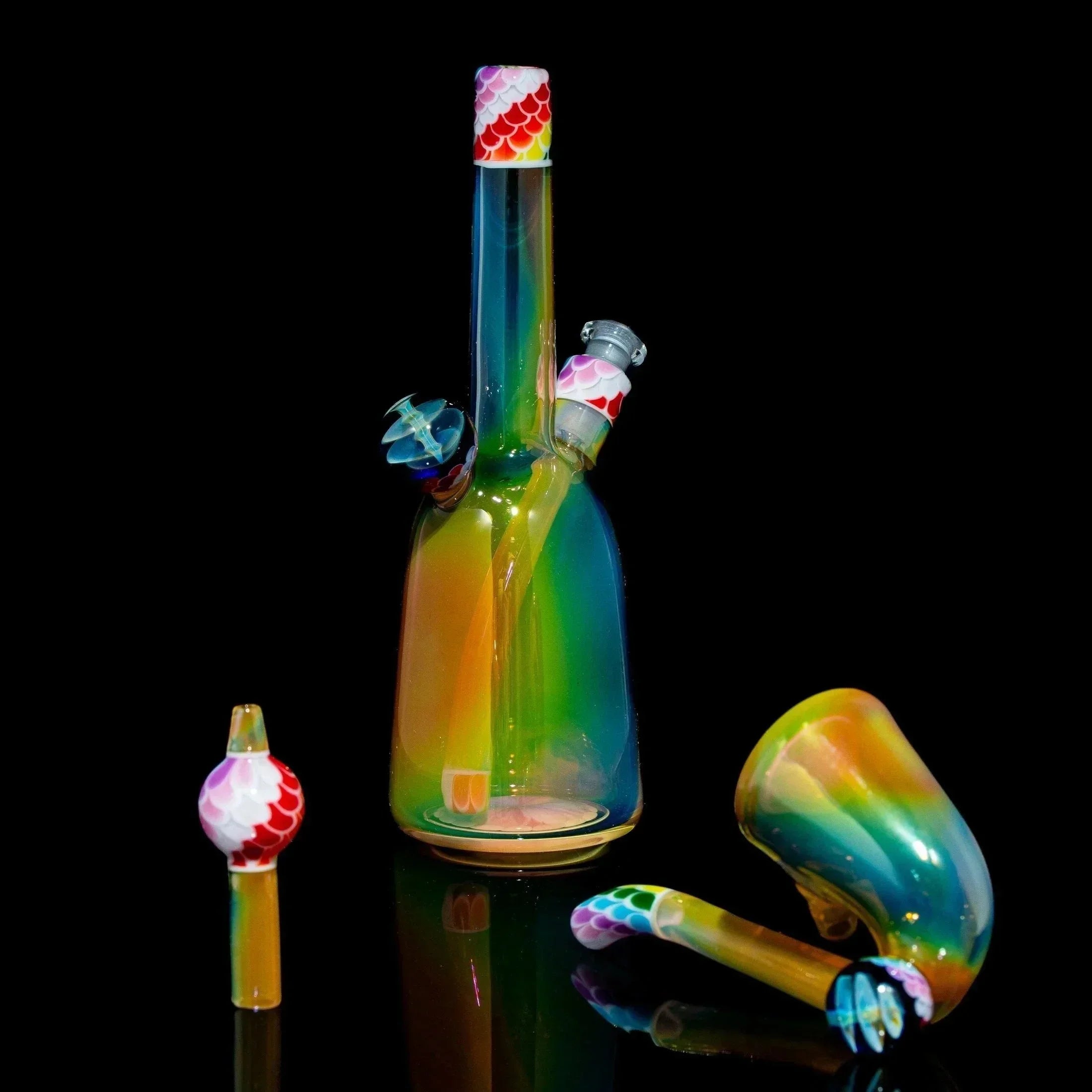 Colorful rainbow glass rig set with scale-patterned accents on a black background.