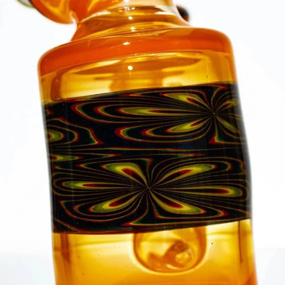 Close-up of orange glass water pipe with intricate black and yellow pattern band.