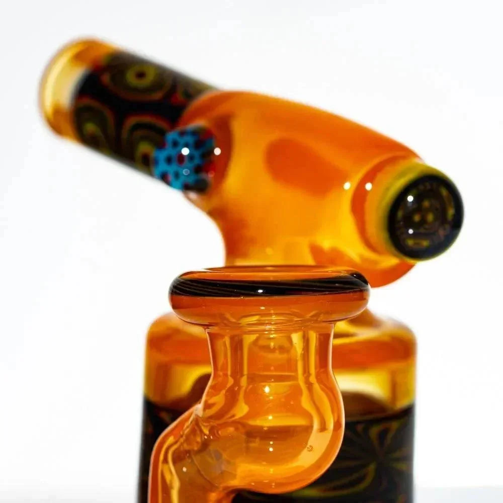 Amber glass mini torch with intricate patterns and colorful accent, close-up view