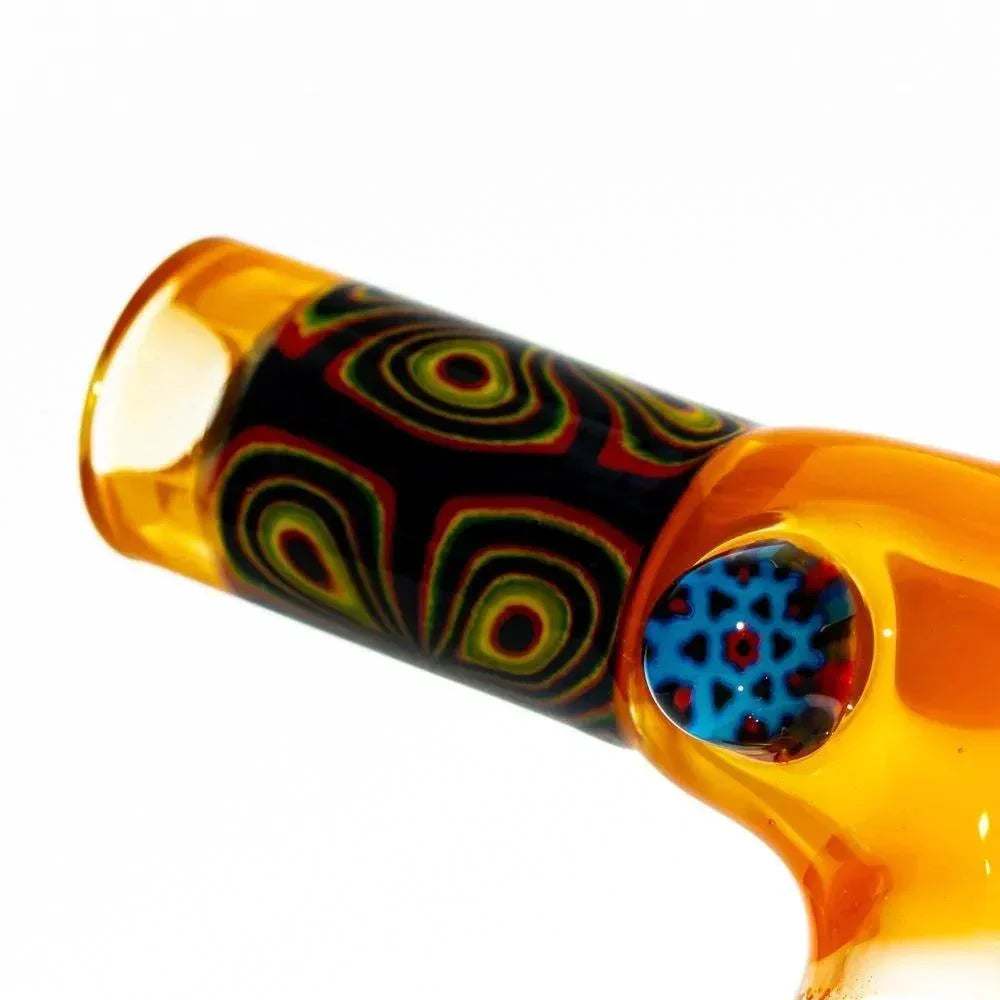 Closeup of amber glass mini torch with colorful psychedelic patterns and blue accent design