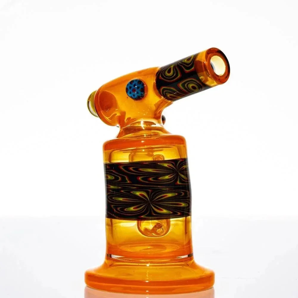 Colorful glass mini torch with orange body and black patterned accents, isolated on white
