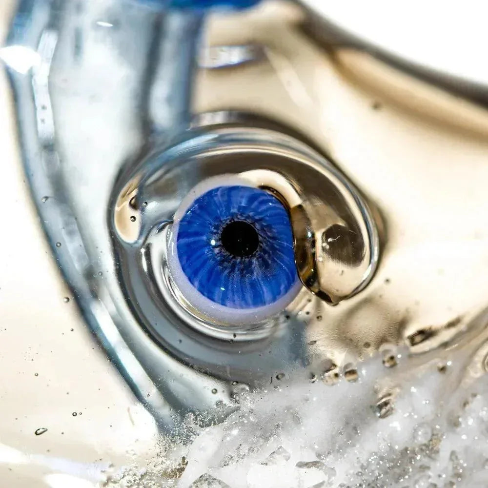 Close-up of intricate glass art pipe featuring a detailed blue eye design