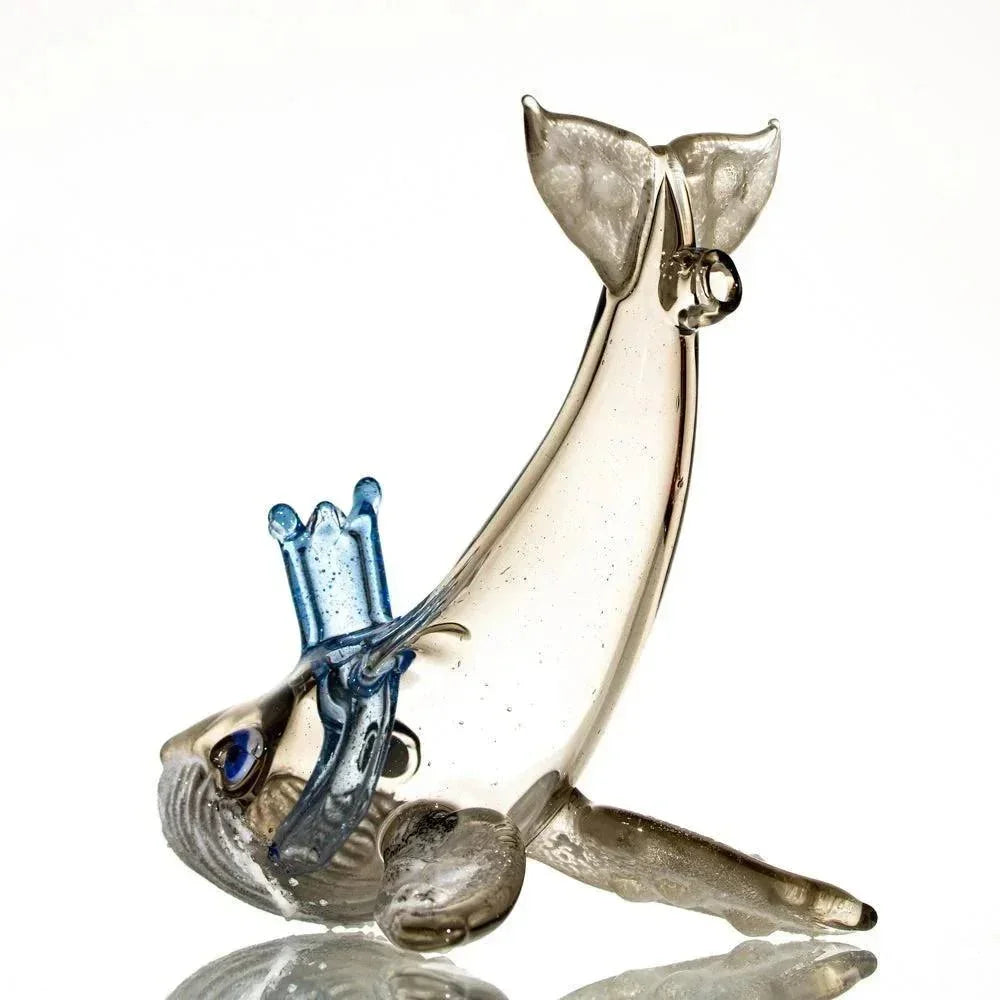 Clear glass humpback whale sculpture with blue accents on white background