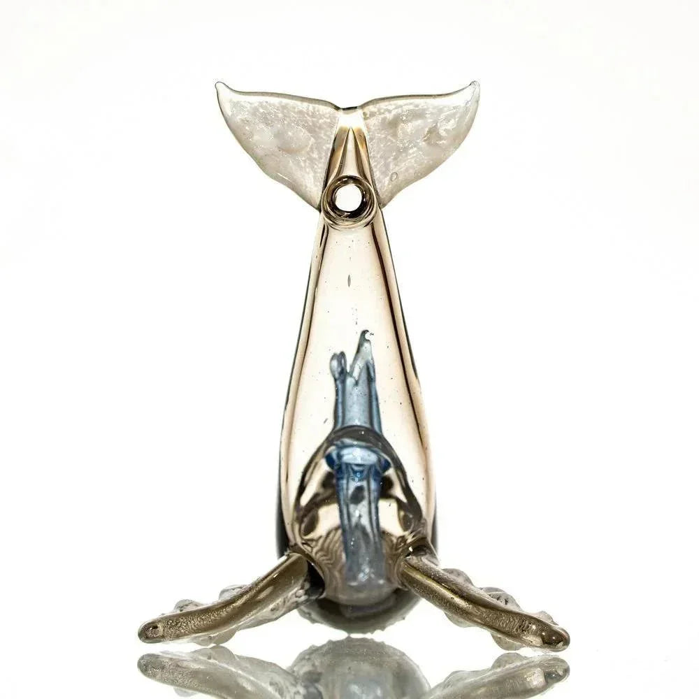 Handcrafted glass pipe shaped like a humpback whale, clear and blue, on white background