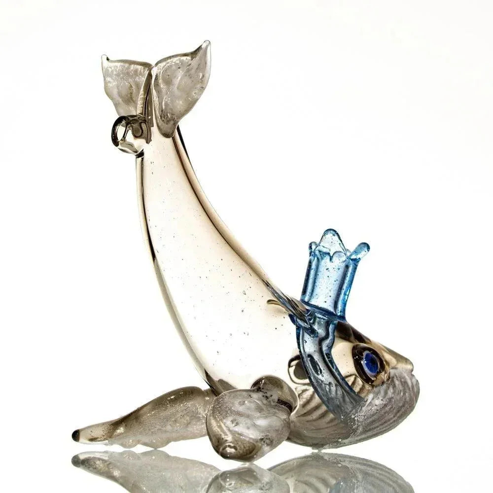 Handblown glass humpback whale pipe with blue and clear detailed accents on white background.