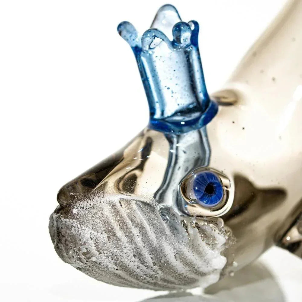 Close-up of a handcrafted glass whale pipe with blue crown detail and textured features