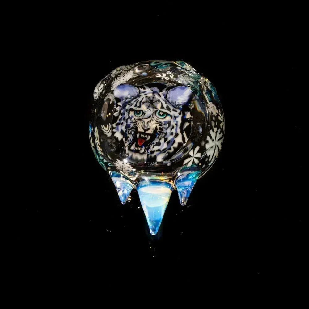 Handcrafted glass carb cap with detailed snow leopard face and snowflake accents on black background