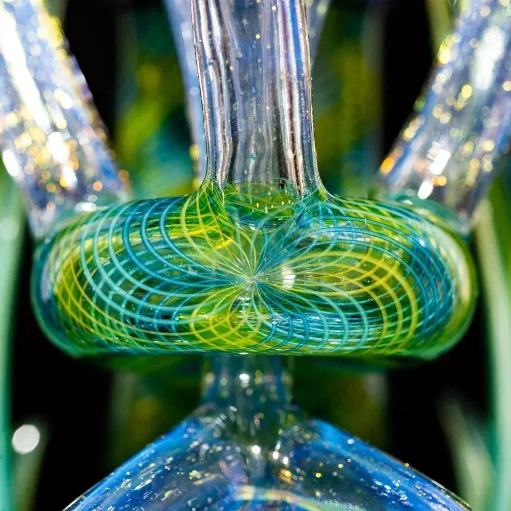 Close-up of colorful dichroic glass art with intricate swirling blue and green patterns