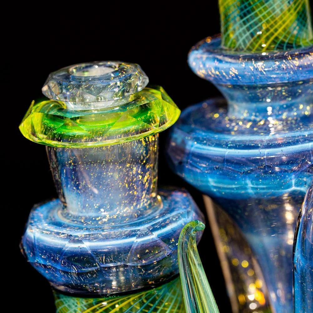 Close-up of iridescent blue and green heady glass water pipe with gold flecks, artistic detail